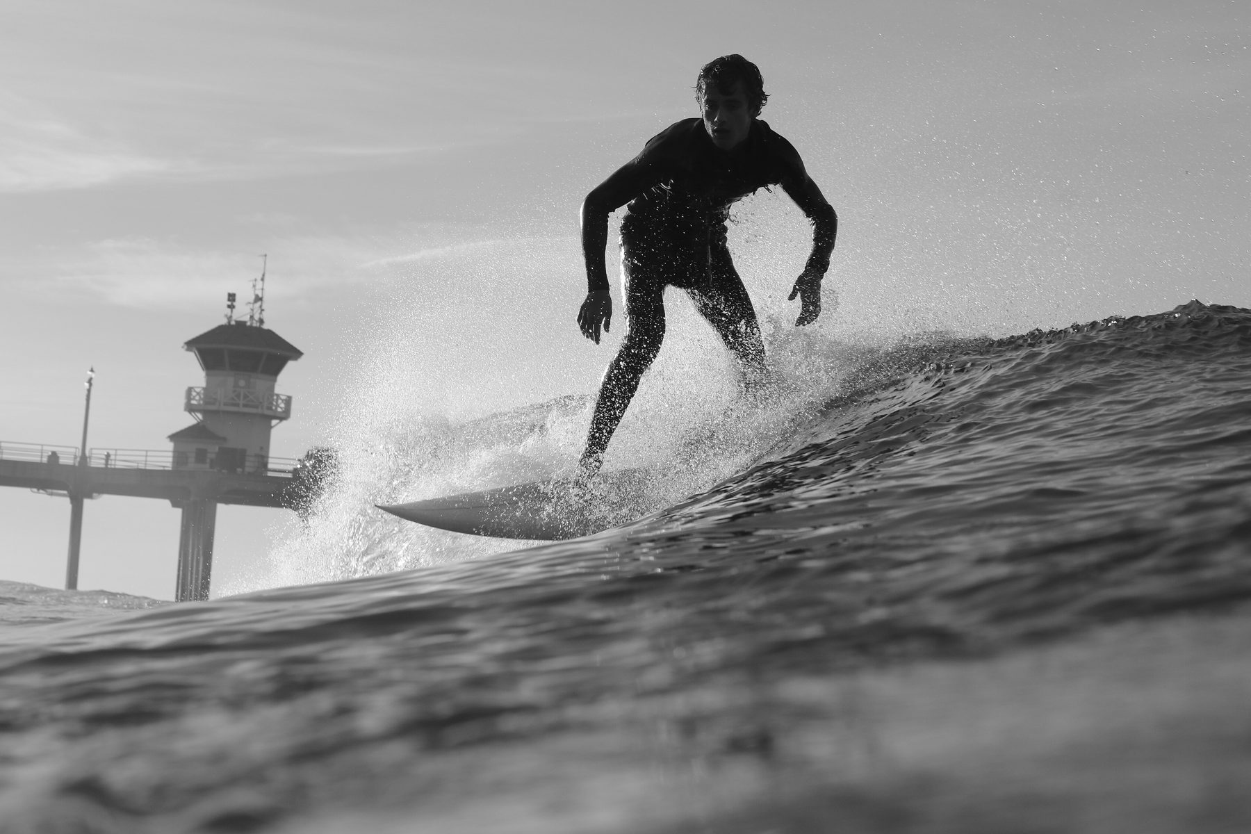 Surfer riding a wave next to the Huntington Beach Pier during a competition