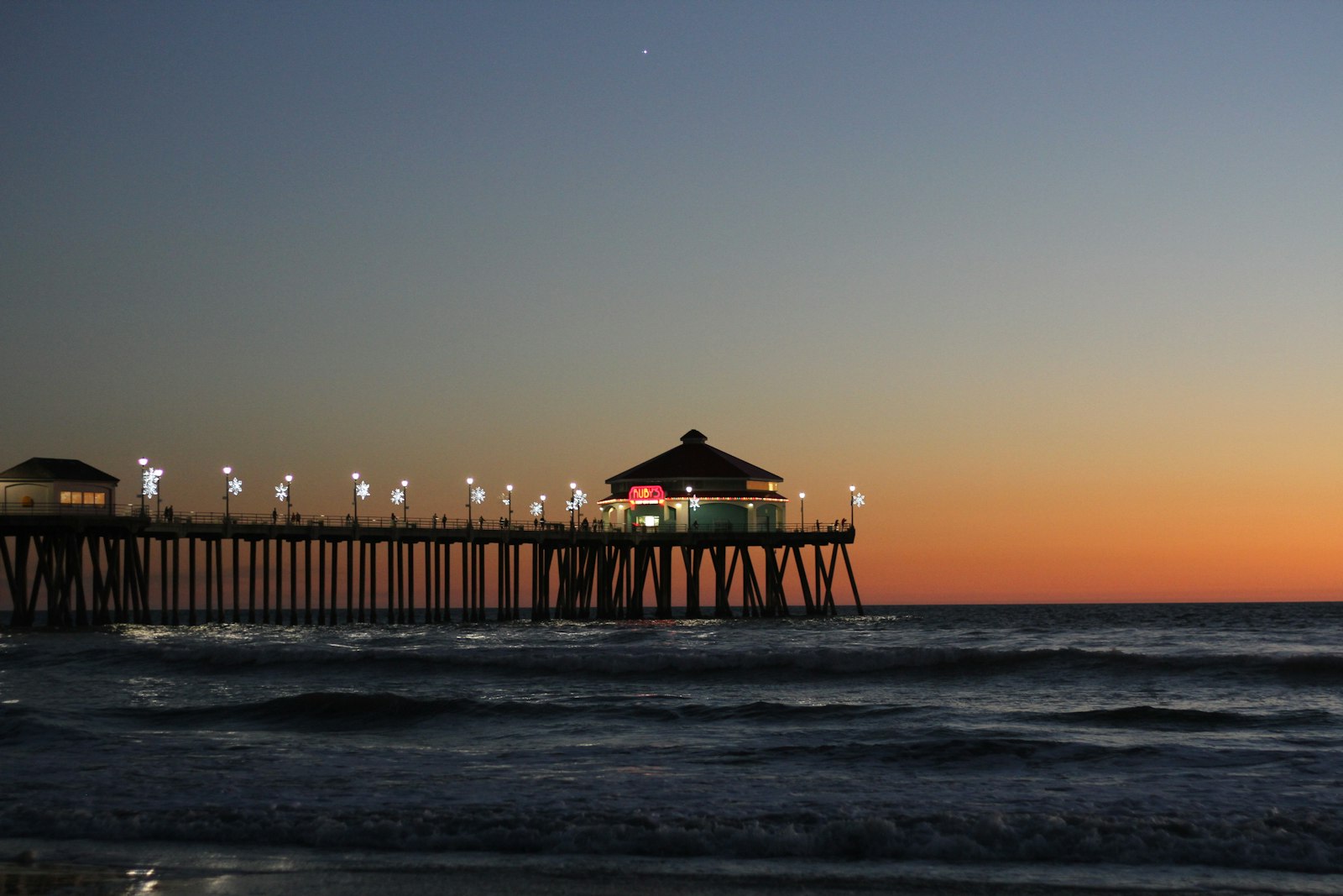 People watching a pastel sunset over the Pacific Ocean in Huntington Beach