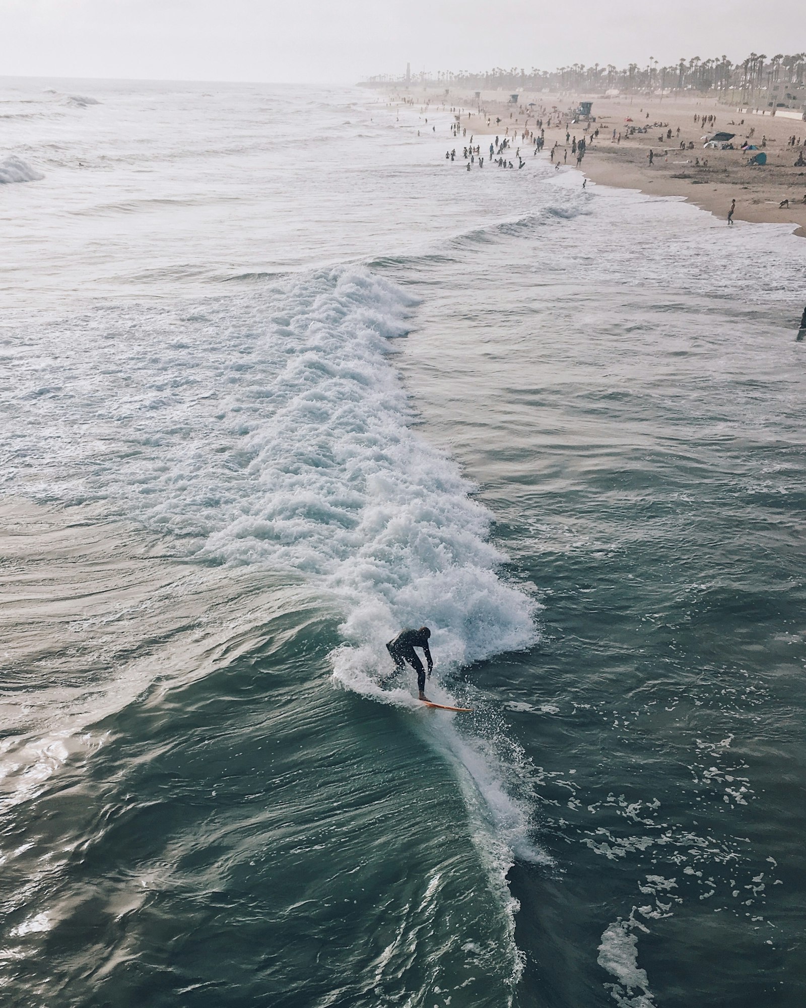 Surfer riding a wave next to the Huntington Beach Pier during a competition