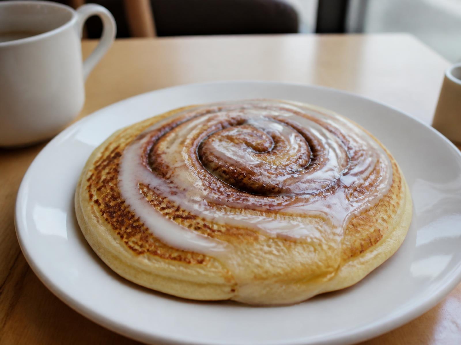 Cinnamon roll pancake with cream cheese glaze on a white plate